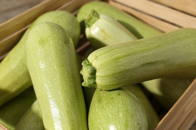 Photo of Fresh ripe zucchinis in wooden crate, closeup