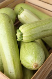 Photo of Fresh ripe zucchinis in wooden crate, closeup