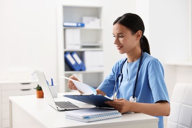 Photo of Smiling nurse working at table in clinic