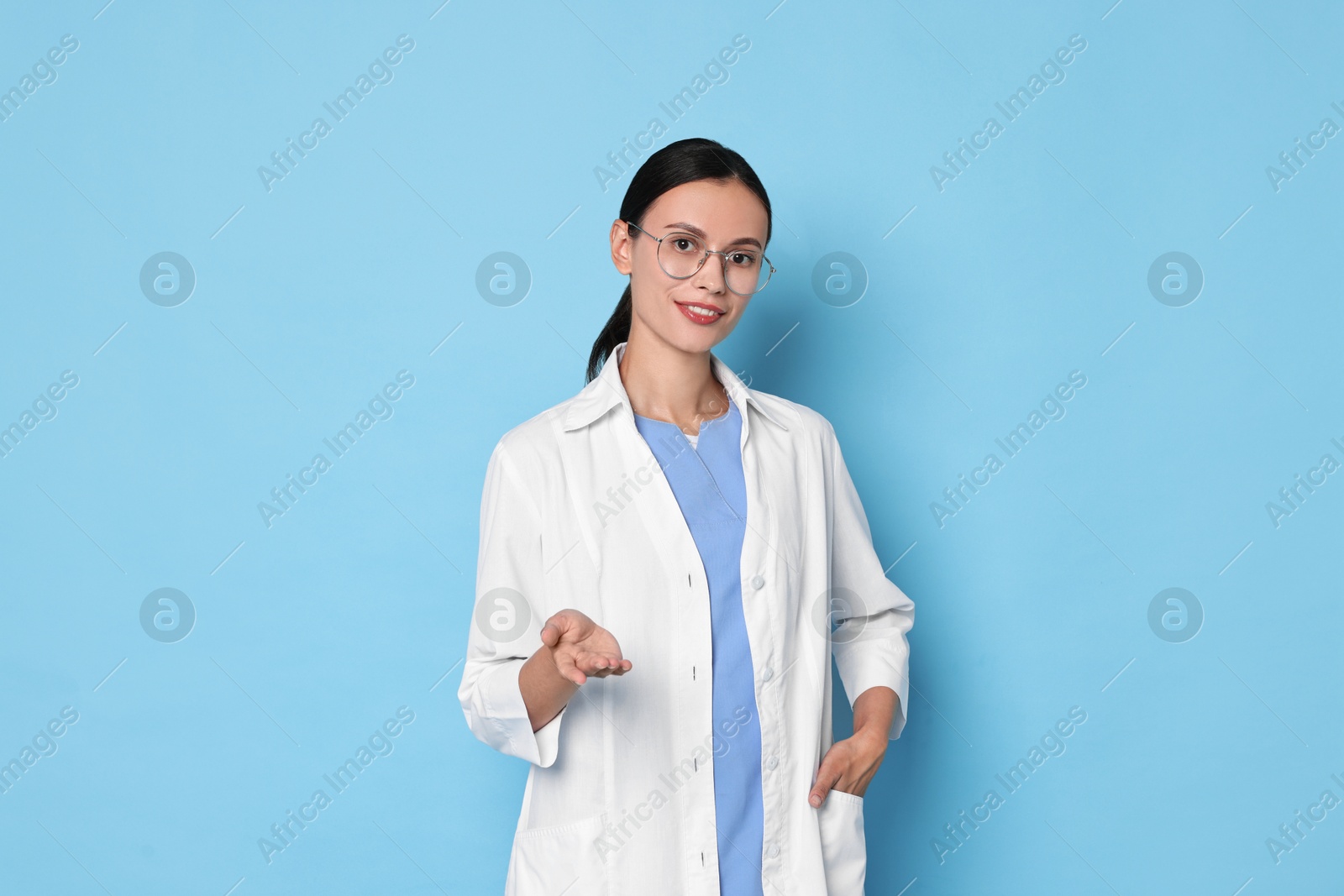 Photo of Smiling nurse holding something on light blue background