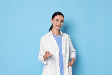 Smiling nurse holding something on light blue background