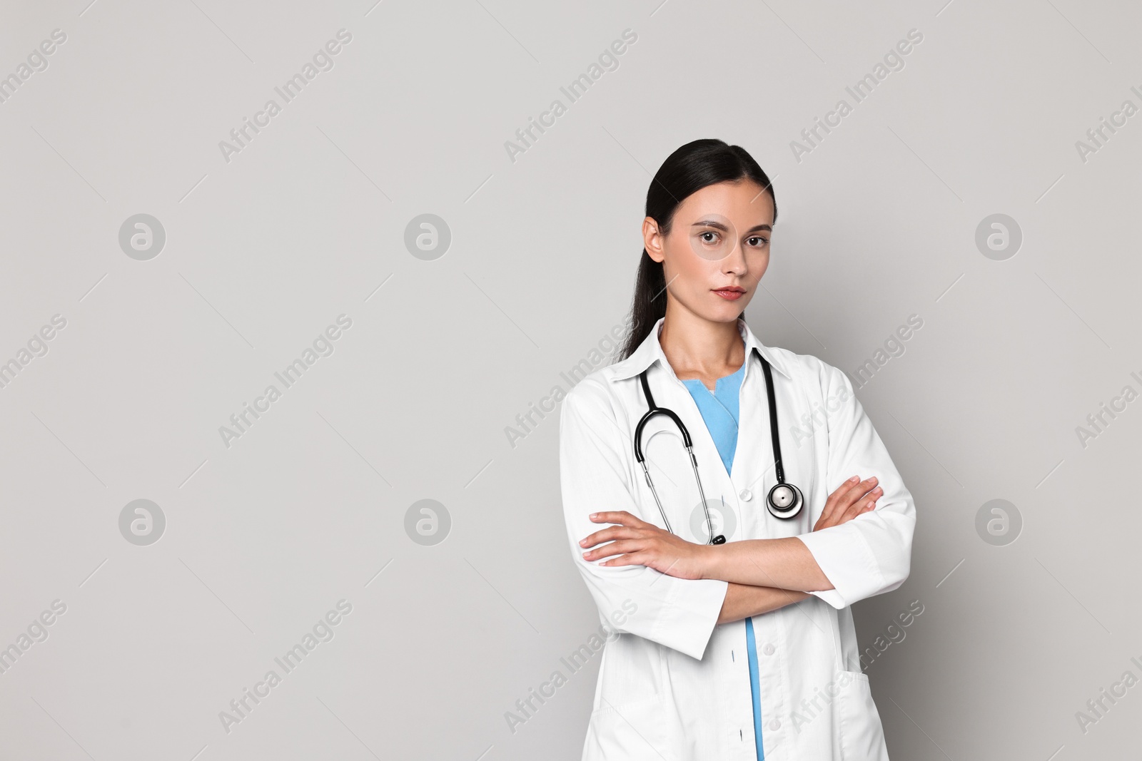 Photo of Beautiful nurse with crossed arms on grey background. Space for text