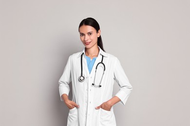 Photo of Smiling nurse in uniform on grey background