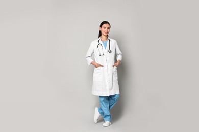 Smiling nurse in uniform on grey background