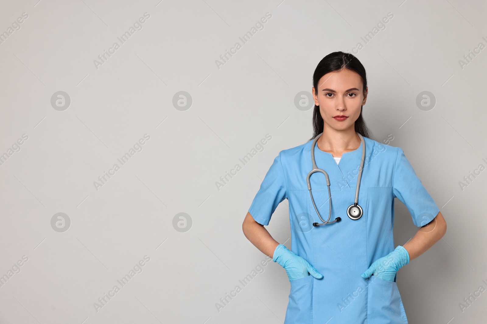 Photo of Beautiful nurse in uniform on grey background. Space for text