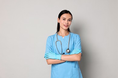 Smiling nurse with crossed arms on grey background