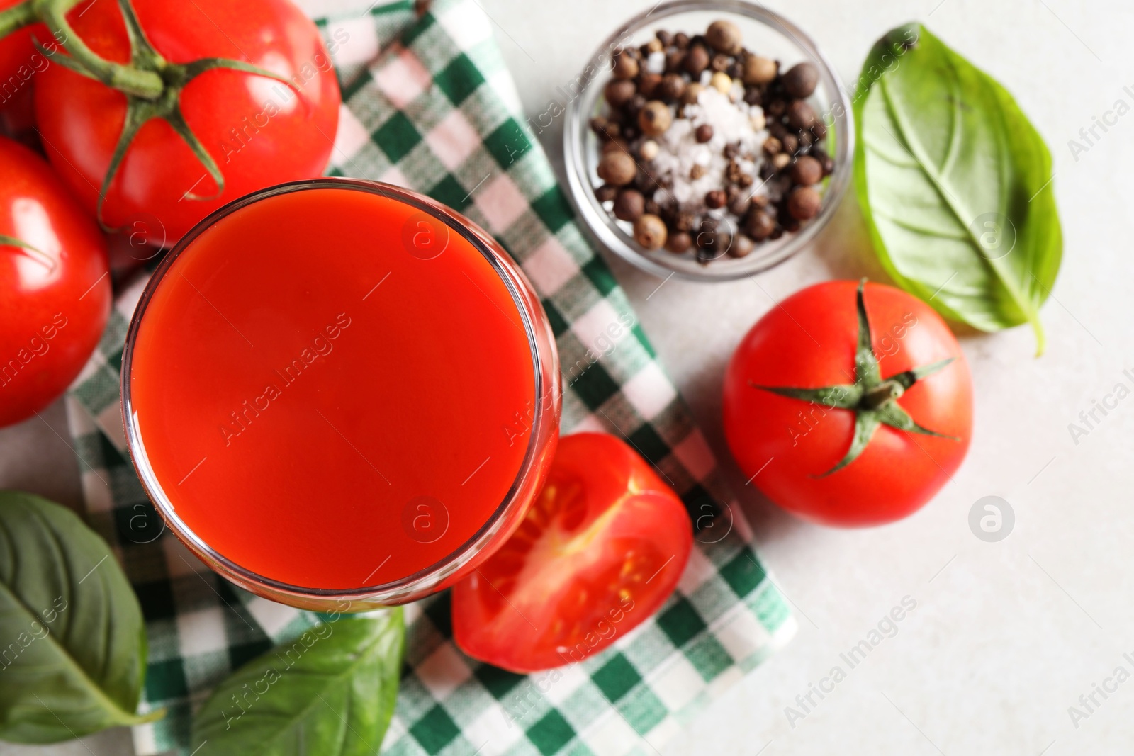 Photo of Tasty tomato juice in glass, spices and fresh vegetables on light table, flat lay