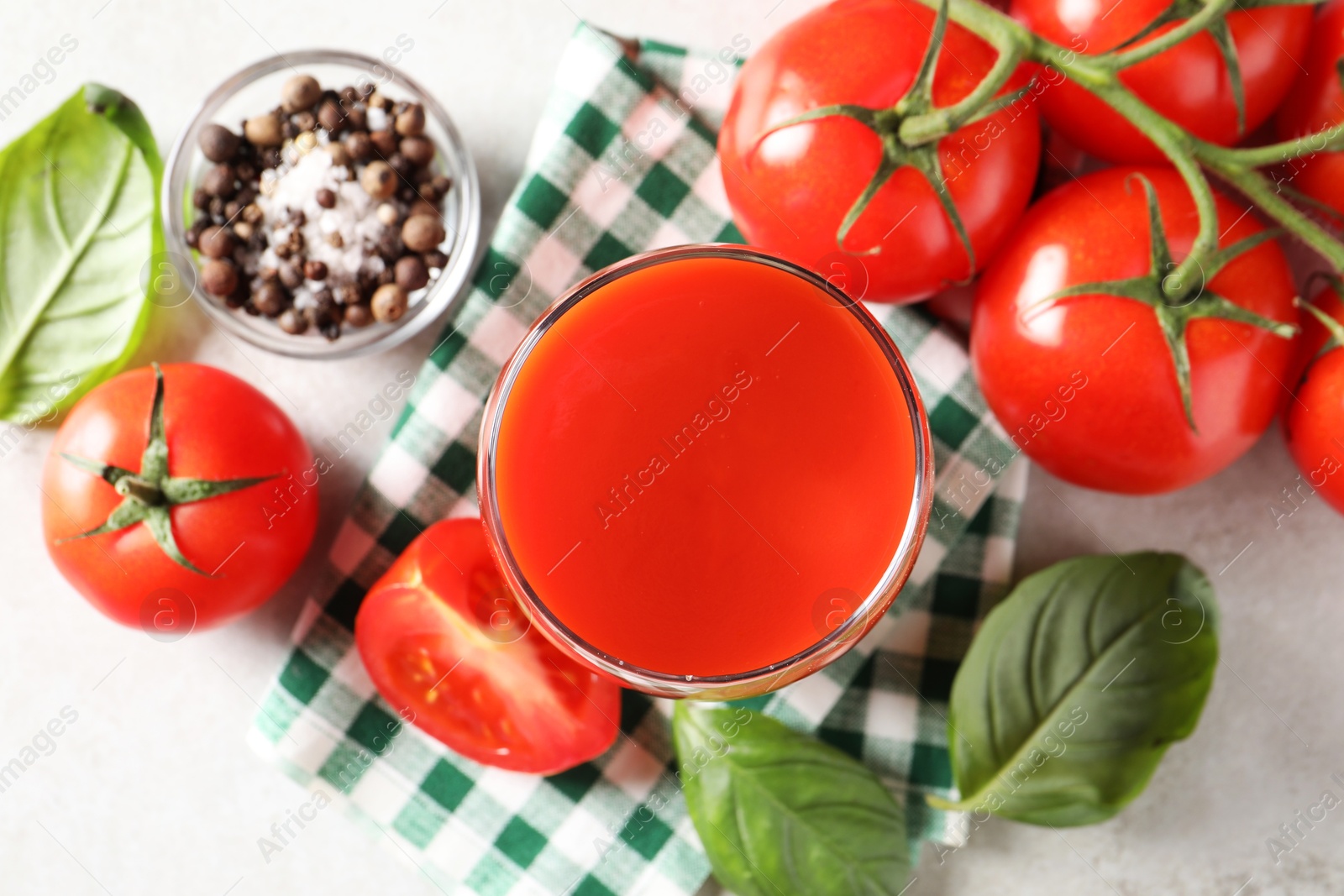 Photo of Tasty tomato juice in glass, spices and fresh vegetables on light table, flat lay