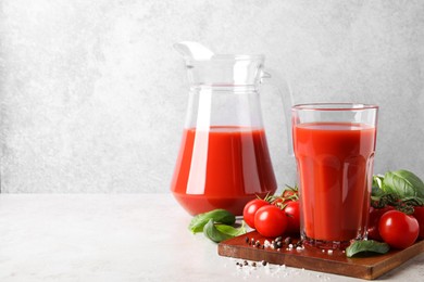 Tasty tomato juice with spices and fresh vegetables on light table, space for text