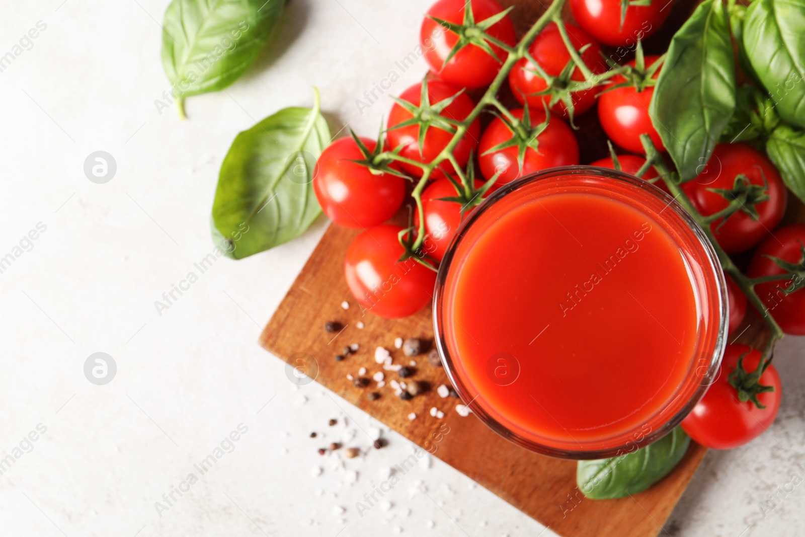 Photo of Tasty tomato juice in glass, spices and fresh vegetables on light table, flat lay. Space for text