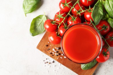 Photo of Tasty tomato juice in glass, spices and fresh vegetables on light table, flat lay. Space for text