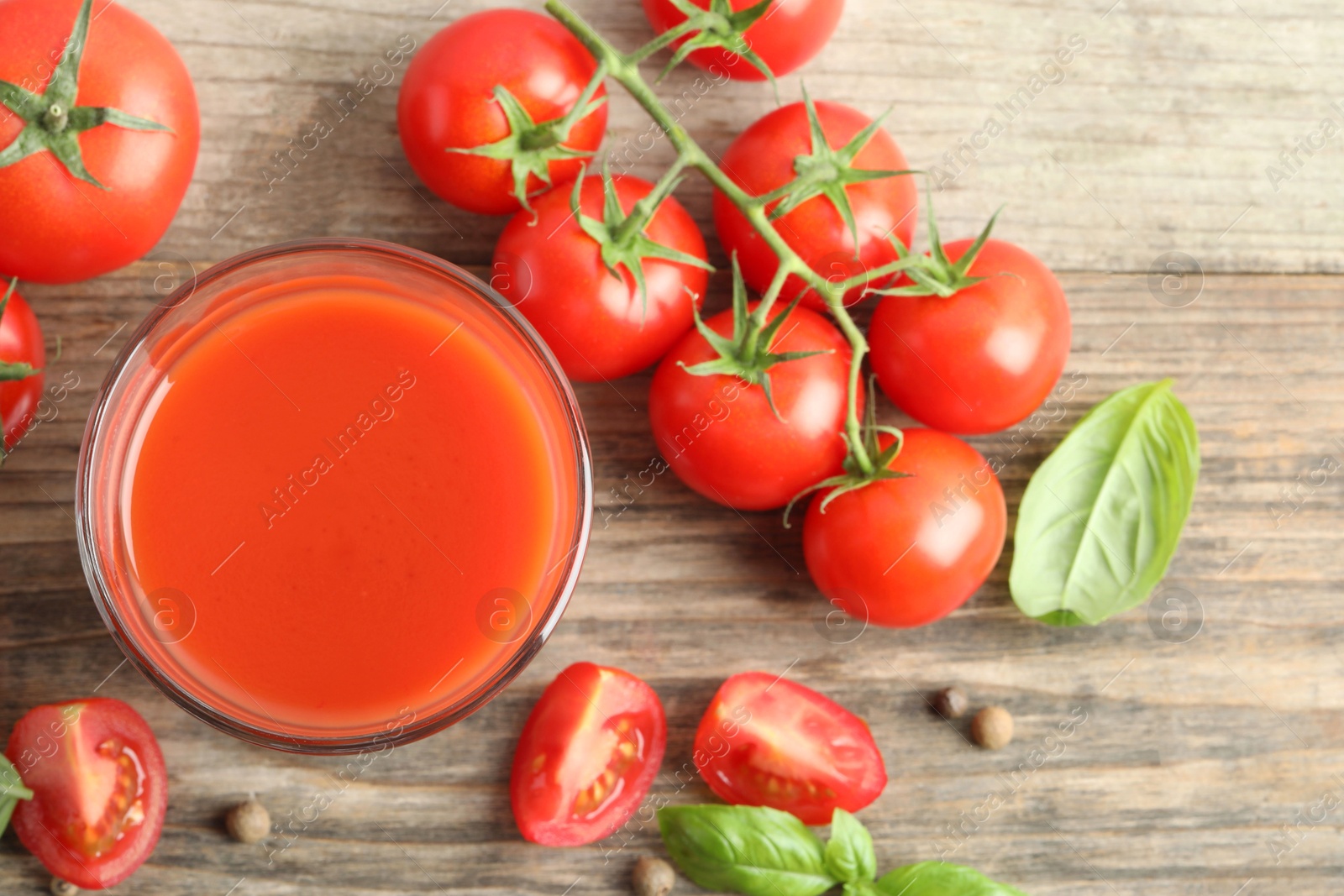 Photo of Tasty tomato juice in glass with fresh vegetables and spices on wooden table, flat lay