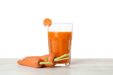 Photo of Fresh carrot juice in glass and vegetables on wooden table against white background