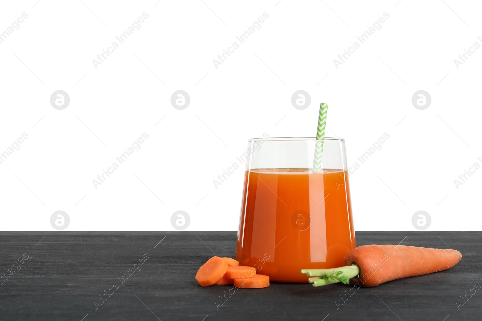 Photo of Fresh carrot juice in glass and vegetables on black wooden table against white background. Space for text