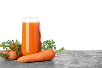 Photo of Fresh carrot juice in glass and vegetables on grey textured table against white background. Space for text