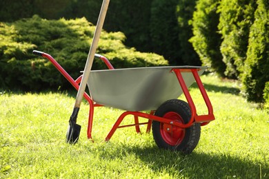 Photo of One wheelbarrow and shovel on green grass in garden