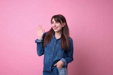 Photo of Happy young woman waving on pink background