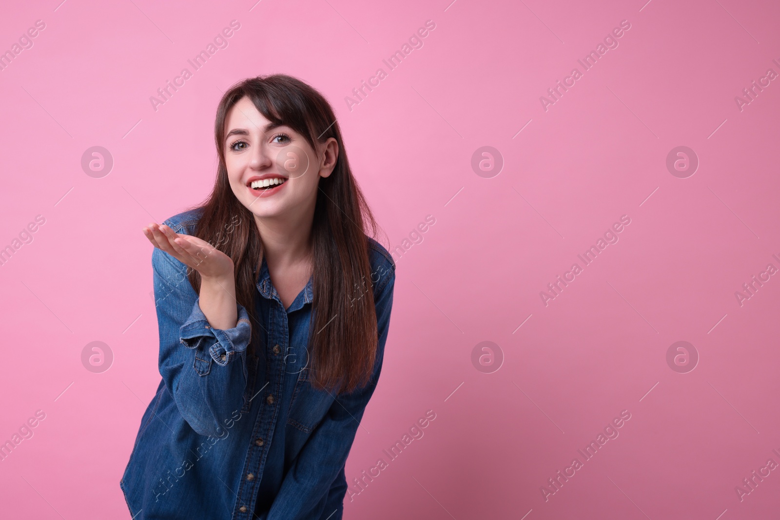 Photo of Beautiful woman blowing kiss on pink background, space for text