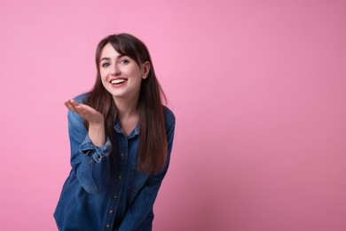 Photo of Beautiful woman blowing kiss on pink background, space for text