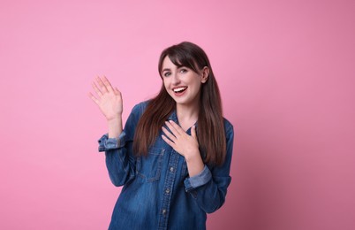 Photo of Happy young woman waving on pink background
