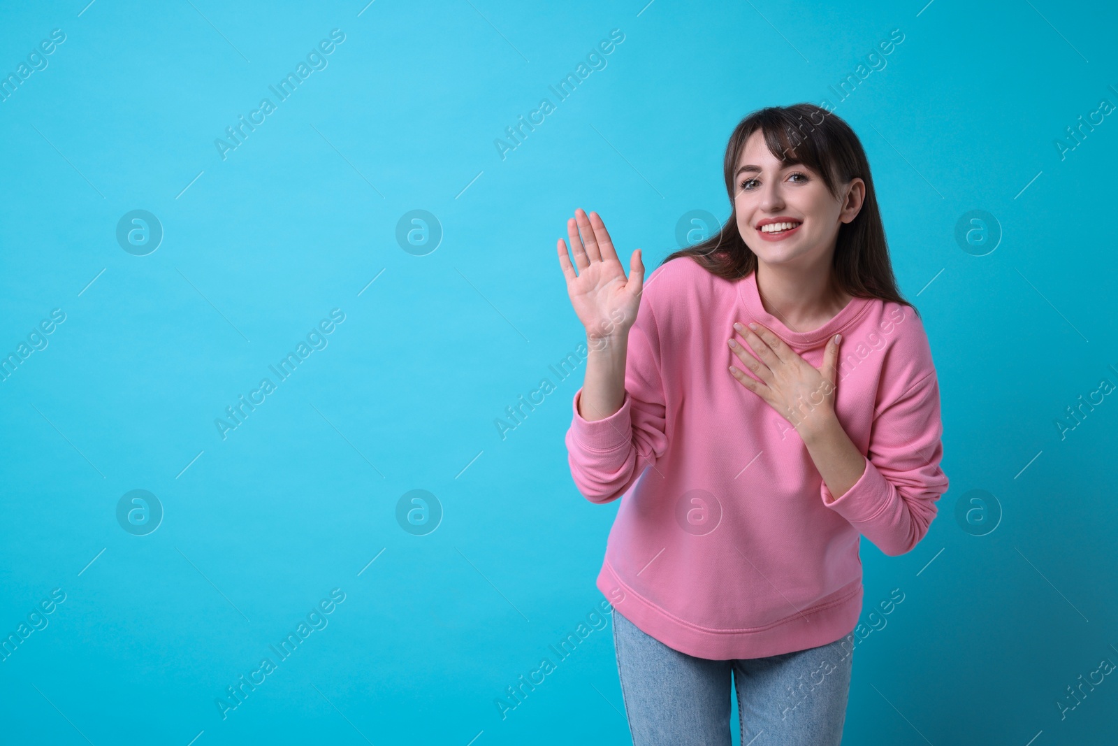 Photo of Happy woman waving on light blue background, space for text