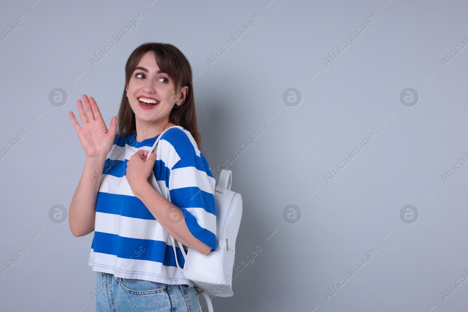 Photo of Happy woman waving on light grey background, space for text