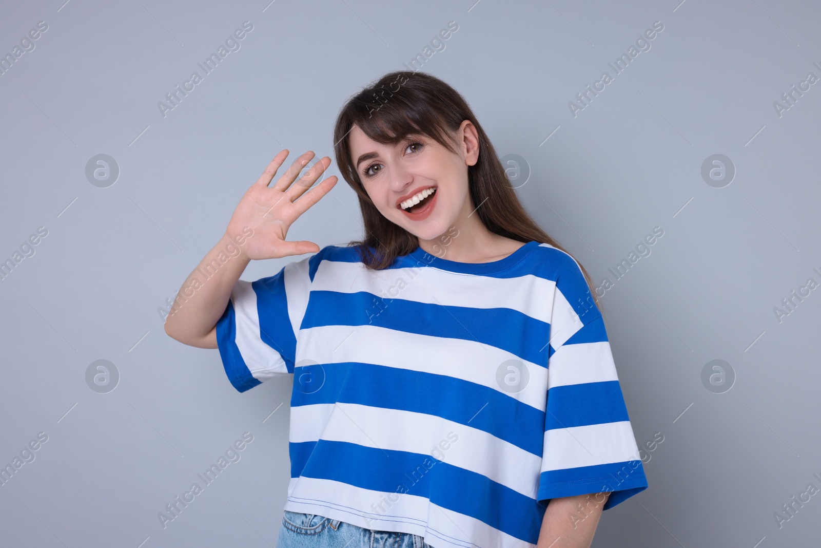 Photo of Happy woman waving on light grey background