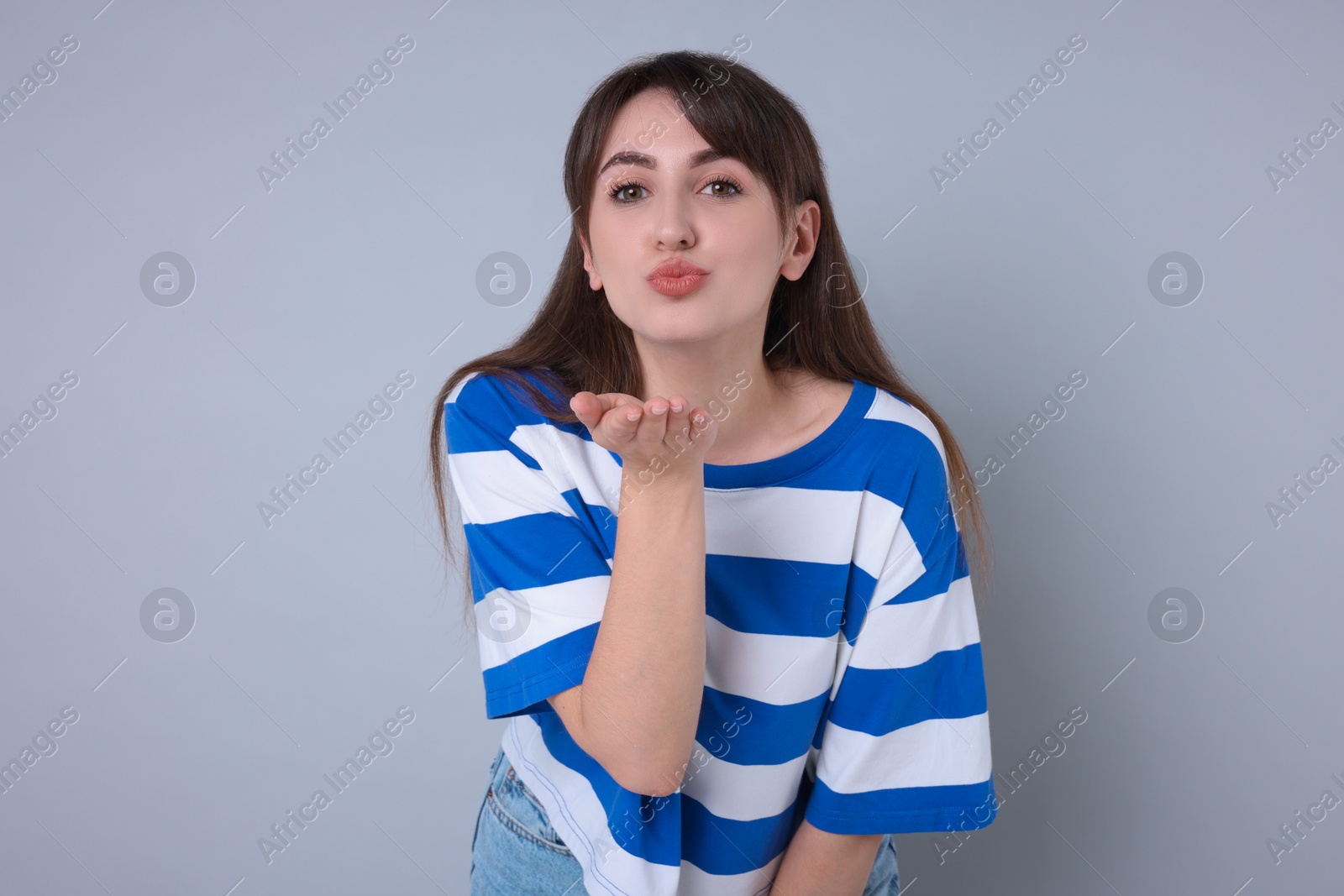 Photo of Beautiful woman blowing kiss on light grey background