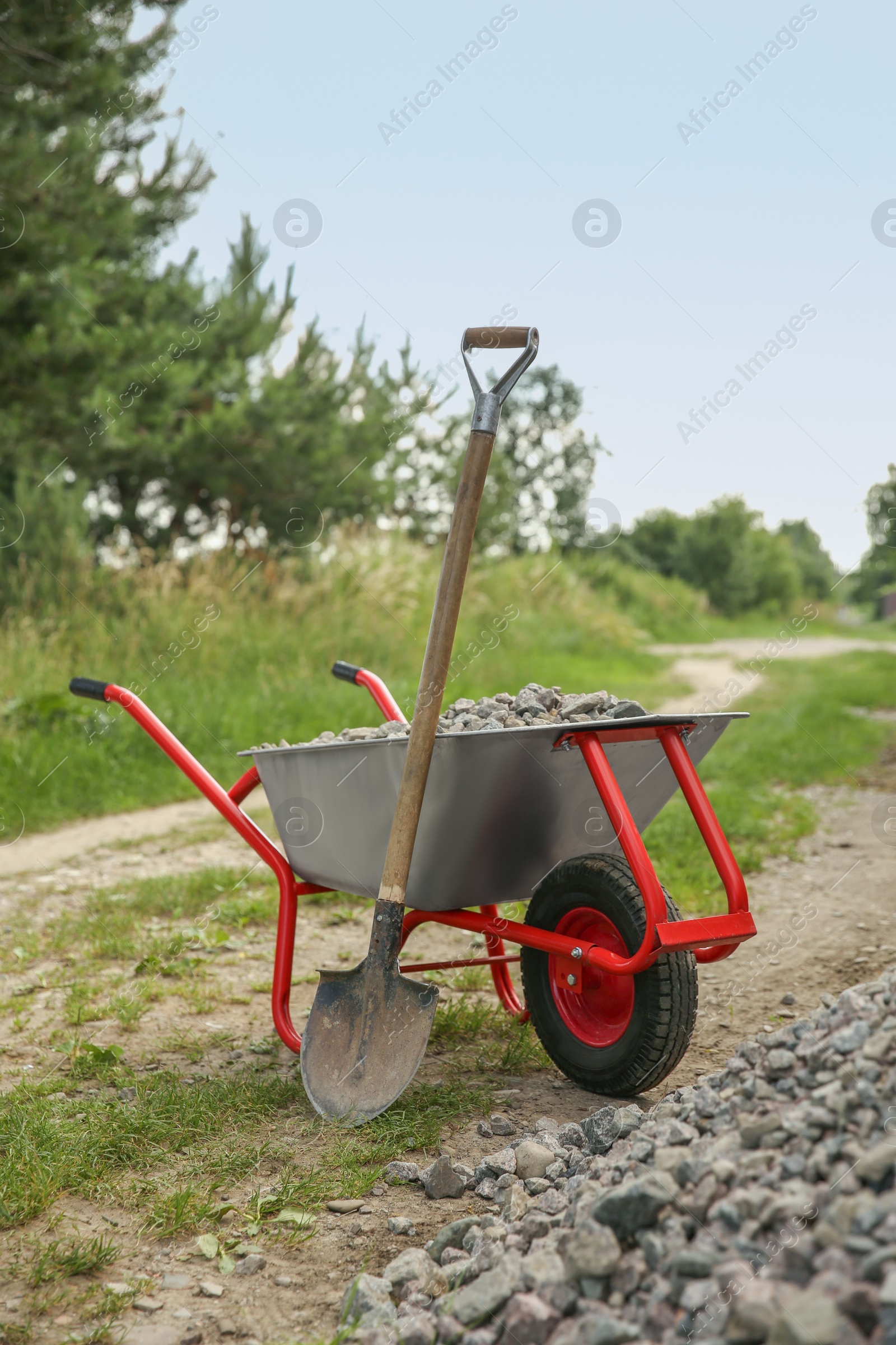 Photo of Wheelbarrow full of stones and shovel outdoors