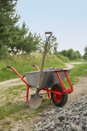 Photo of Wheelbarrow full of stones and shovel outdoors