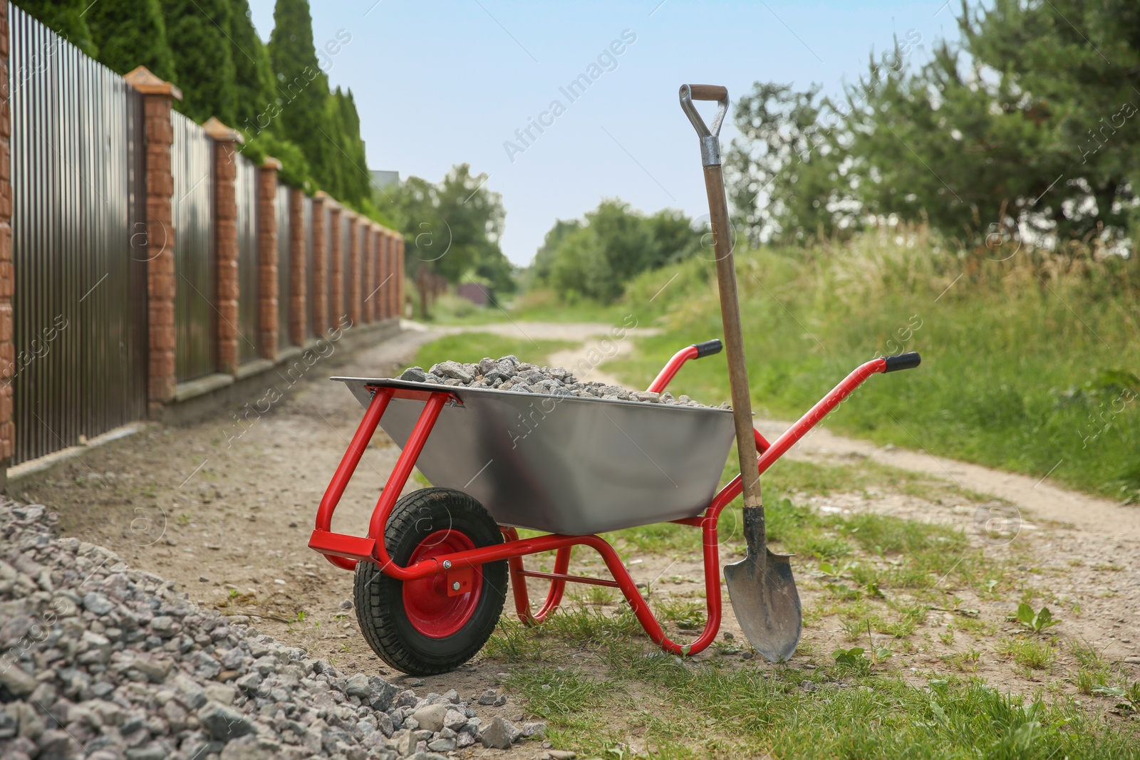 Photo of Wheelbarrow full of stones and shovel outdoors