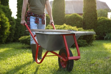 Photo of Man with wheelbarrow and gardening tools outdoors on sunny day, closeup