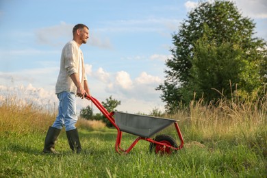 Farmer with wheelbarrow outdoors on sunny day