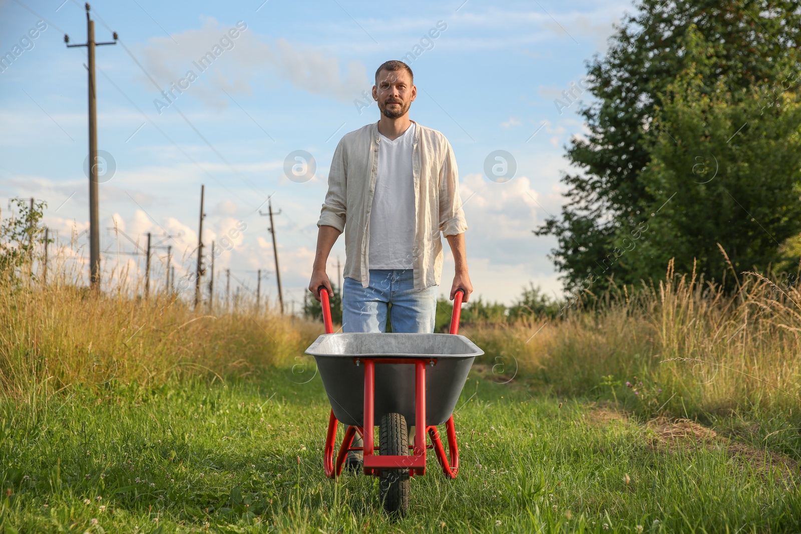 Photo of Farmer with wheelbarrow outdoors on sunny day