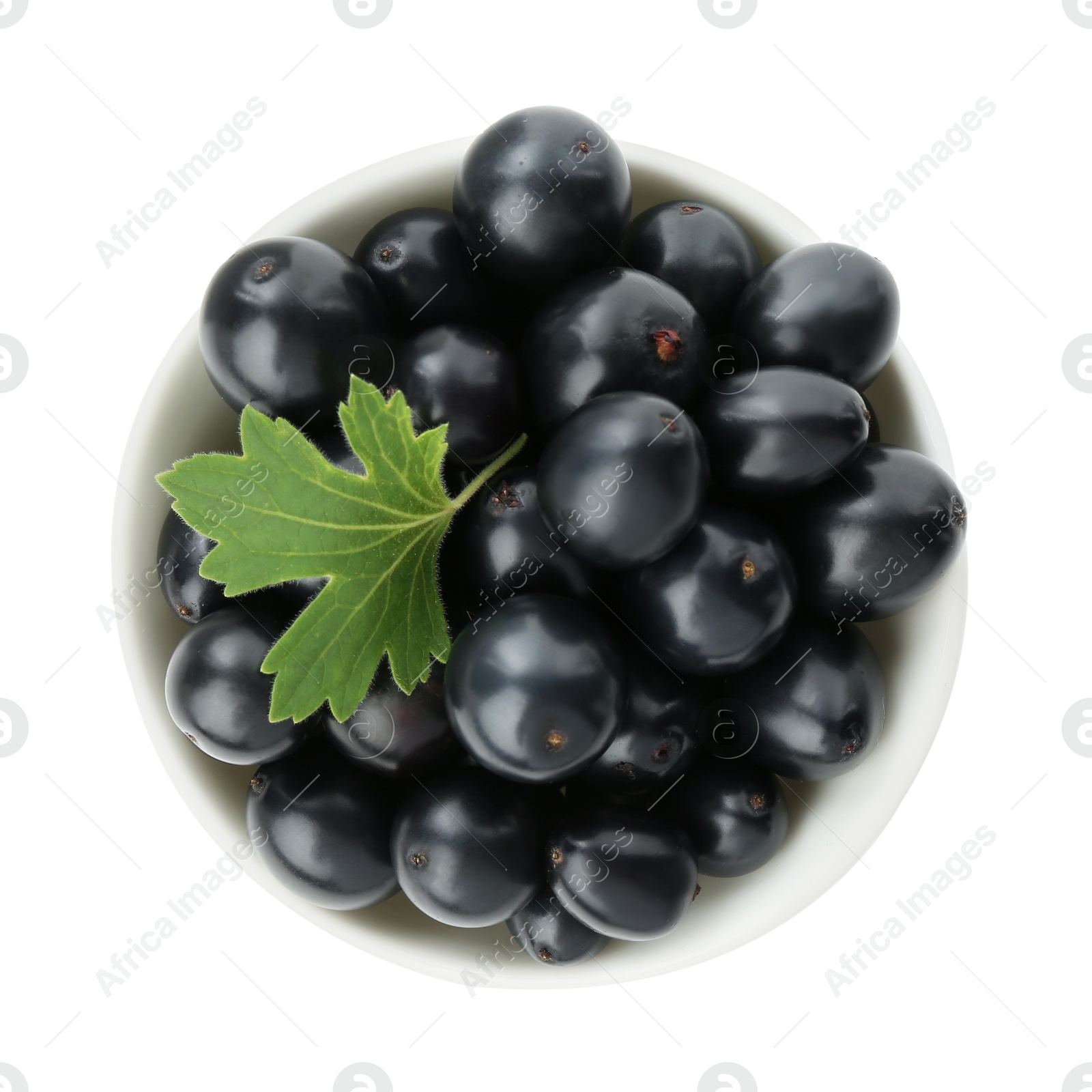 Photo of Bowl of ripe blackcurrants and green leaf isolated on white, top view