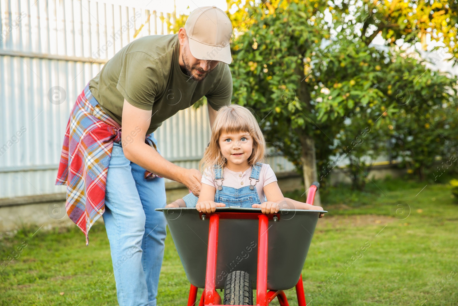 Photo of Father near wheelbarrow with kids in backyard