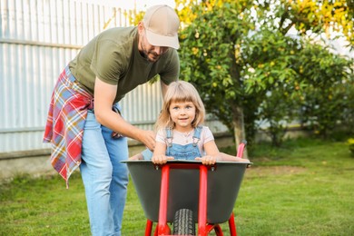 Father near wheelbarrow with kids in backyard