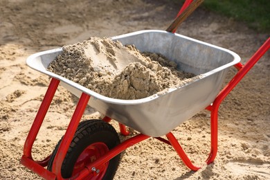 Photo of Metal wheelbarrow with pile of sand outdoors