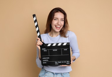 Photo of Making movie. Happy woman with clapperboard on beige background