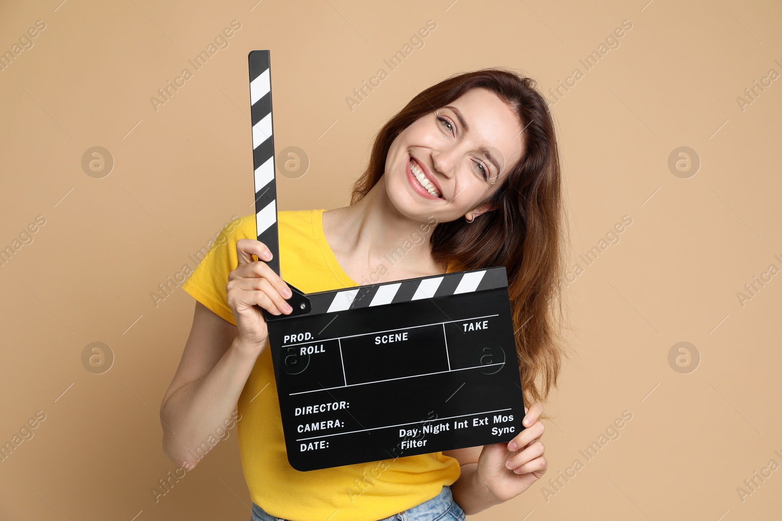 Photo of Making movie. Smiling woman with clapperboard on beige background