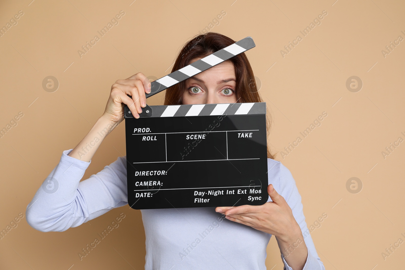 Photo of Making movie. Woman with clapperboard on beige background