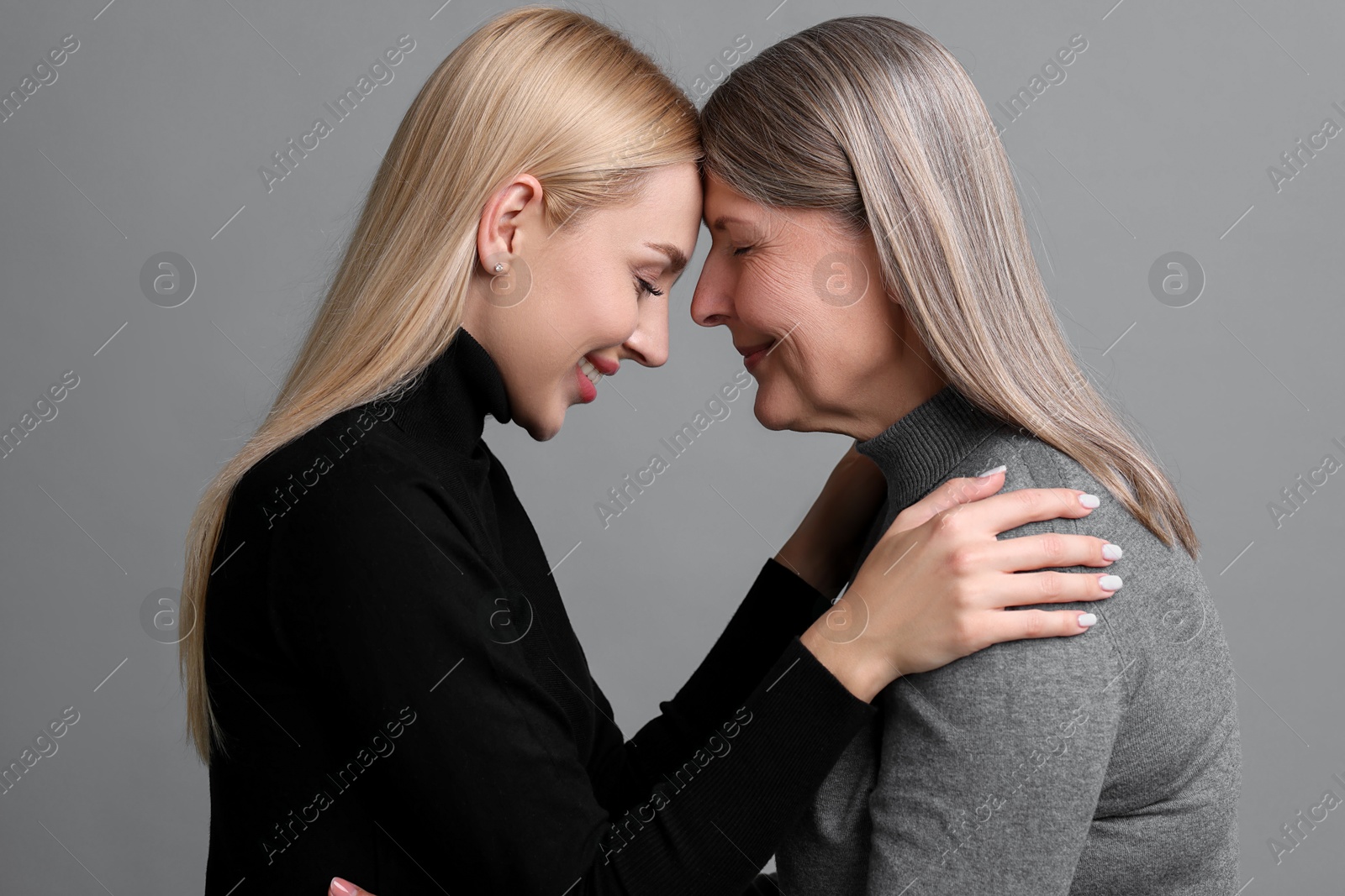 Photo of Family portrait of young woman and her mother on grey background