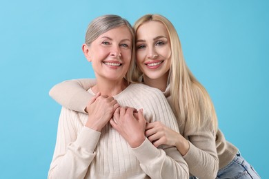 Photo of Family portrait of young woman and her mother on light blue background