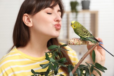 Photo of Woman with bright parrot indoors. Exotic pet