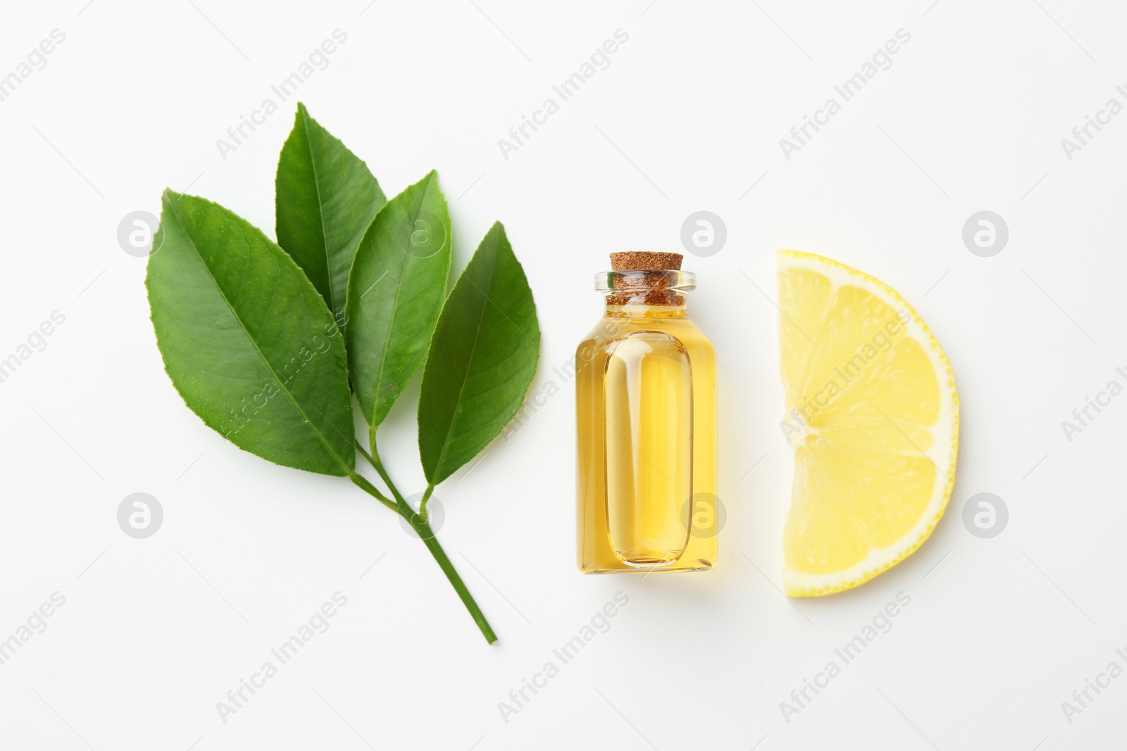 Photo of Bottle of essential oil, lemon and green leaves on white background, flat lay