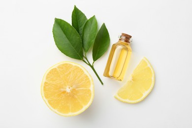 Bottle of essential oil, lemon and green leaves on white background, flat lay