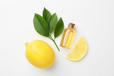 Photo of Bottle of essential oil, lemon and green leaves on white background, flat lay