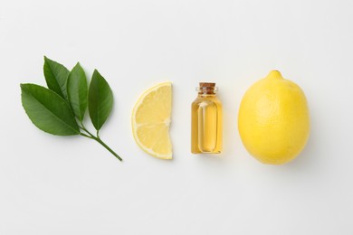 Photo of Bottle of essential oil, lemon and green leaves on white background, flat lay