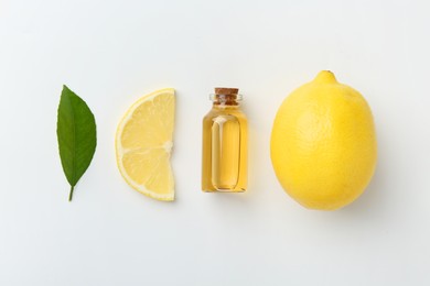 Photo of Bottle of essential oil, lemon and green leaf on white background, flat lay