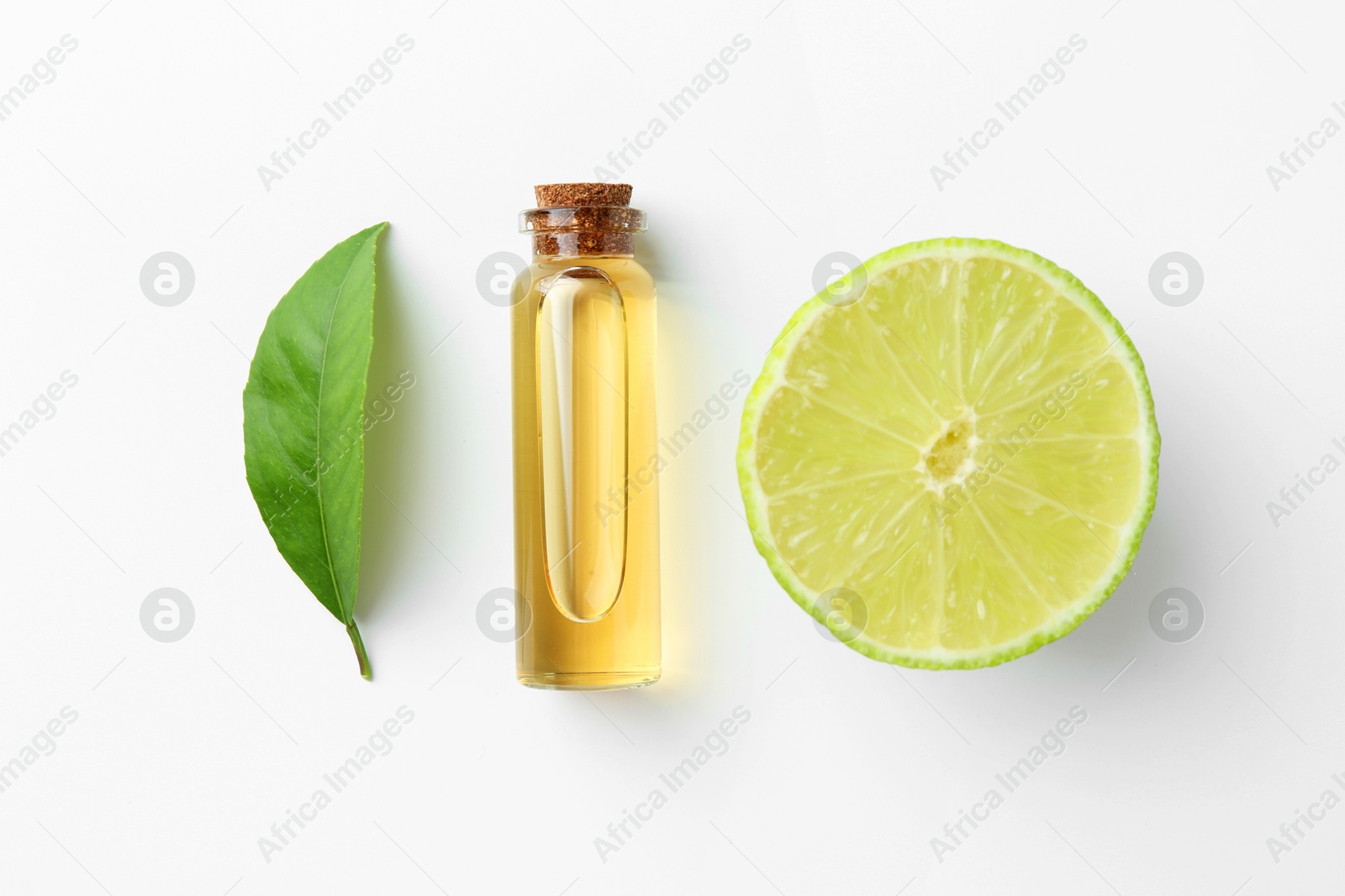 Photo of Bottle of essential oil, lime and green leaf on white background, flat lay